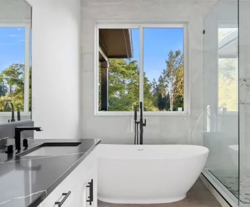 Elegant Bathroom With Freestanding Tub And Dark Countertops 800x665